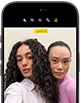 جهاز iPhone&nbsp;18&nbsp;Pro، بلون أسود، الجهة الخارجية الأمامية، عارضتان تتخذان وضعية التصوير أمام الكاميرا، استعراضاً لكاميرا Center&nbsp;Stage الأمامية