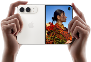 جهاز iPhone Duo، لون أبيض النجوم، يدان تحملان الجهاز في الوضع الأفقي، مفتوح، اللوحة اليسرى تعرض نظام كاميرا مزدوجة 48MP Fusion، اللوحة اليمنى تعرض شخصاً تُلتقط صورته على الشاشة الخارجية، يمكن لهذا الشخص رؤية وجهه لأن الصورة تُلتقط باستخدام ميزة Duo Preview