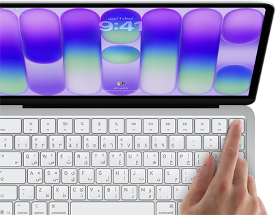 جهاز MacBook Neo، لون فضي، يعرض شاشة تسجيل الدخول، إصبع شخص على مستشعر بصمة الإصبع في الزاوية العلوية اليسرى من لوحة المفاتيح