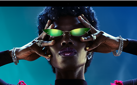 شاشة ملونة على MacBook Pro تُظهر شخصاً يتفاعل بحماس مع الجمهور في إحدى الحفلات، ما يبرز حيوية شاشة ريتنا ليكويد XDR النابضة بالحياة