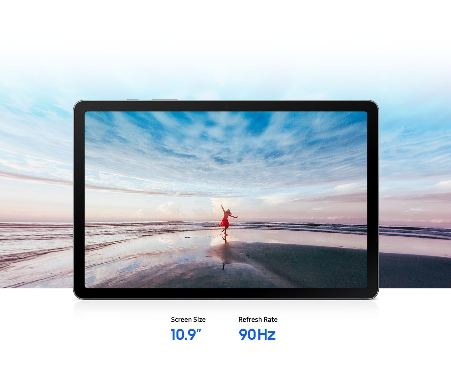Galaxy Tab S10 Lite displayed horizontally showing a vivid image of a woman in red dress on the beach with arms outstretched against a blue sky and ocean horizon, expressing a free-spirited mood. The expansive scene extends beyond the screen edges, highlighting the large 10.9-inch display and immersive viewing experience that brings content to life. Text reads Screen Size 10.9-inch, Refresh Rate 90 Hz.